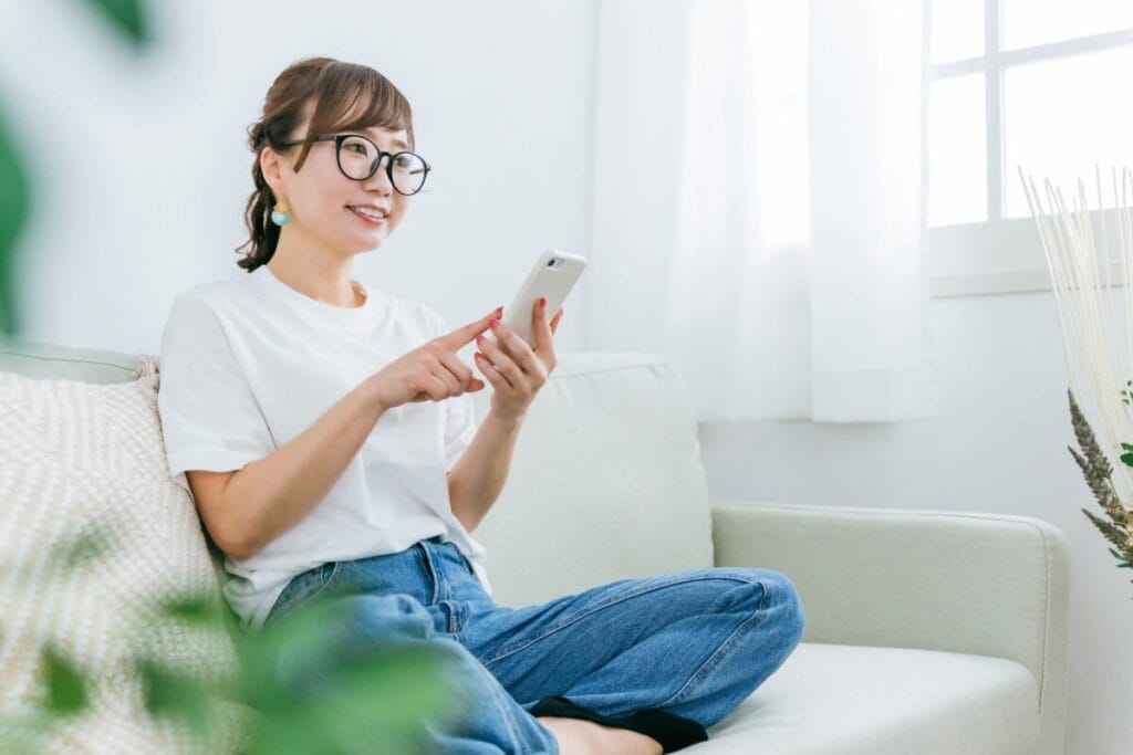 ソファに座ってスマホのアプリを使う女性